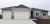 A grey exterior rambler home with a three car garage.